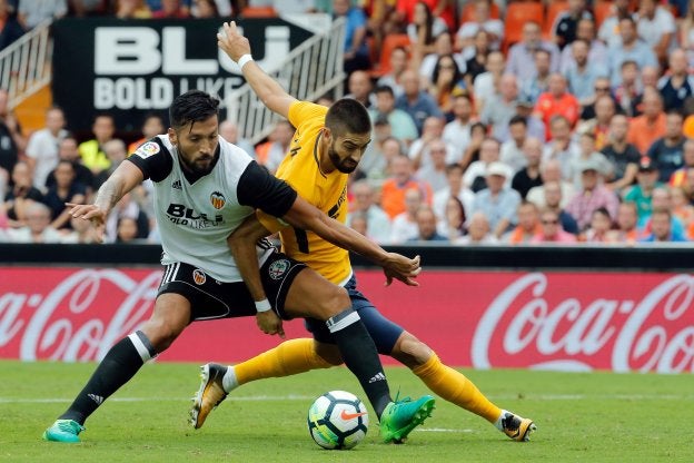 Garay y Carrasco pelean por el balón ayer en Mestalla.