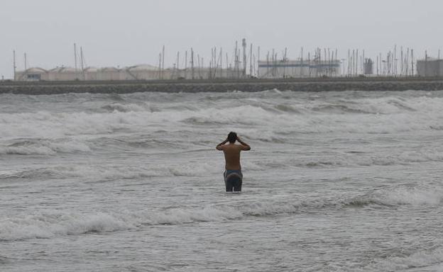 Un joven se baña en la playa de Valencia.