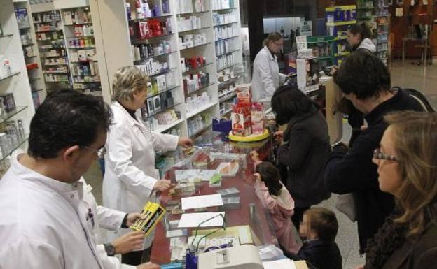 Profesionales atendiendo a clientes en una farmacia valenciana.