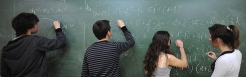 Dos jóvenes resuelven ecuaciones en una pizarra.