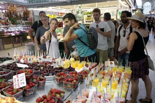 Un grupo de clientes ante un puesto en el Mercado Central este verano.