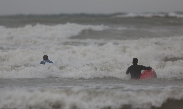 Dos deportistas desoyen las recomendaciones y se internan en la Malvarrosa en pleno temporal.