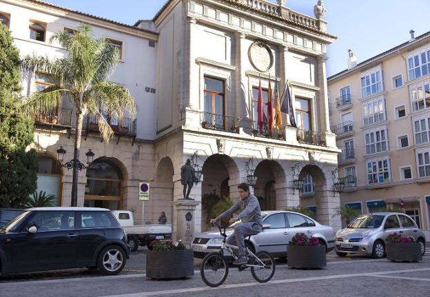 Un vecino de Gandia circula en bicicleta por la plaza Major, frente al Ayuntamiento. / lp