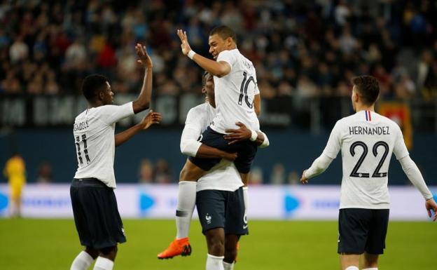 Pogba sostiene en brazos a Mbappé, que choca la mano con Dembélé. /Reuters