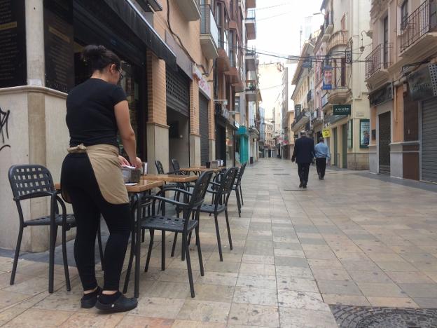 Una empleada de una cafetería repone un servilletero en la calle Mayor en la tarde de ayer. / lp