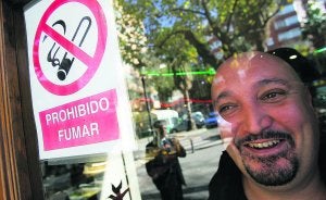 Shahin junto al adhesivo que prohibe fumar dentro de su bar en la calle Antonio Suárez. :: JESÚS SIGNES/