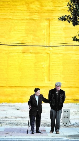 Una pareja de ancianos pasea junto a uno de los numerosos solares del barrio de La Viña. :: NACHO GARCÍA / AGM/