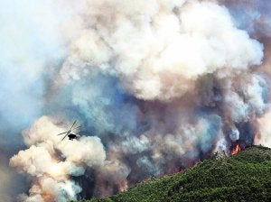 Un helicóptero sobrevuela el incendio forestal declarado en Llocnou de Sant Jeroni, en medio de una inmensa humareda./ Efe | R. Francés/