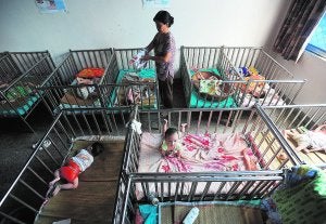Una trabajadora atiende a los bebés de un orfanato de Wuhu, en China. / AFP/