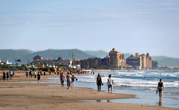 Ciudadanos pasean por la playa de Alboraya, este domingo./MANUEL BRUQUE/EFE