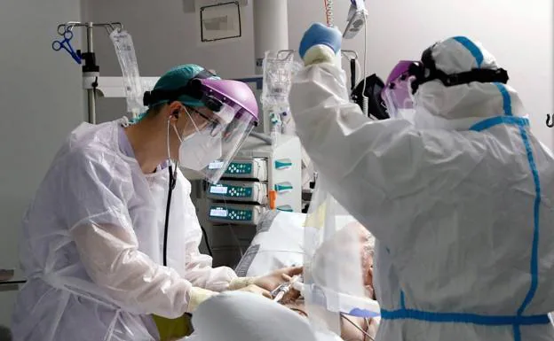 Sanitarios atienden a un paciente en la unidad de cuidados intensivos del hospital La Fe de Valencia./EFE/ JUAN CARLOS CÁRDENAS