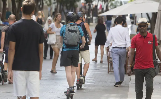 Usuarios de scooters en una calle peatonal de Valencia. 