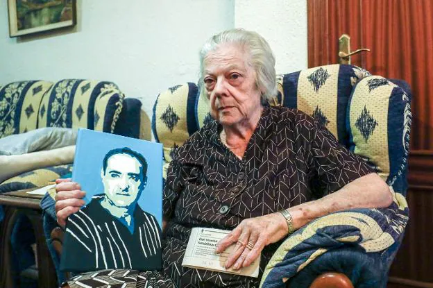 Victoria junto a la necrológica que publica todos los años para su esposo y un retrato de él. 